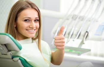woman on the dentist chair holding her thumb up